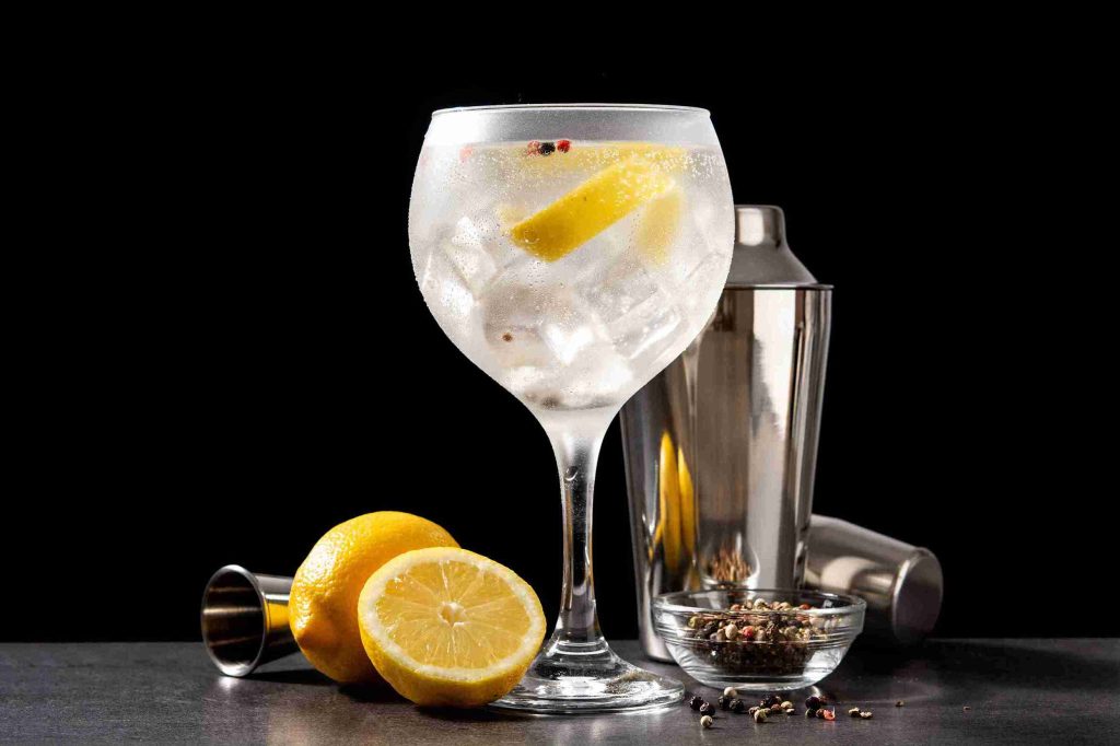 Una copa de balón con una coctelera, limones y especias